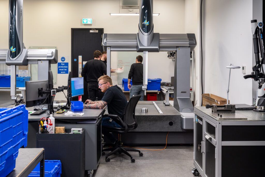 Photo of a man using CAM Assist within AutoDesk Fusion on a shop floor next to a machine.